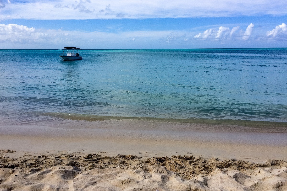 Boat floating in ocean with beach in foreground