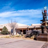 Statue of a Native American dancer outside a museum with an adobe facade in Santa Fe