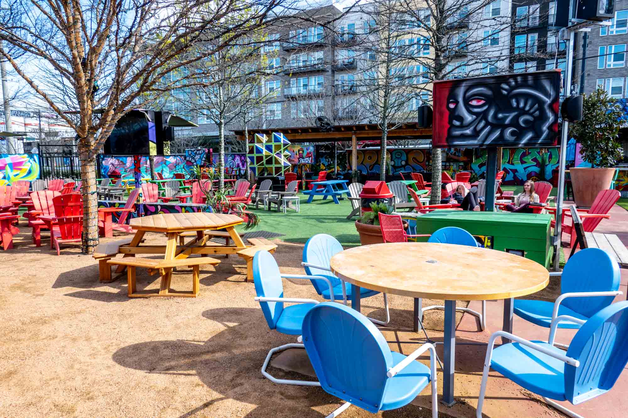 Tables and chairs in a beer garden with graffiti decorations.