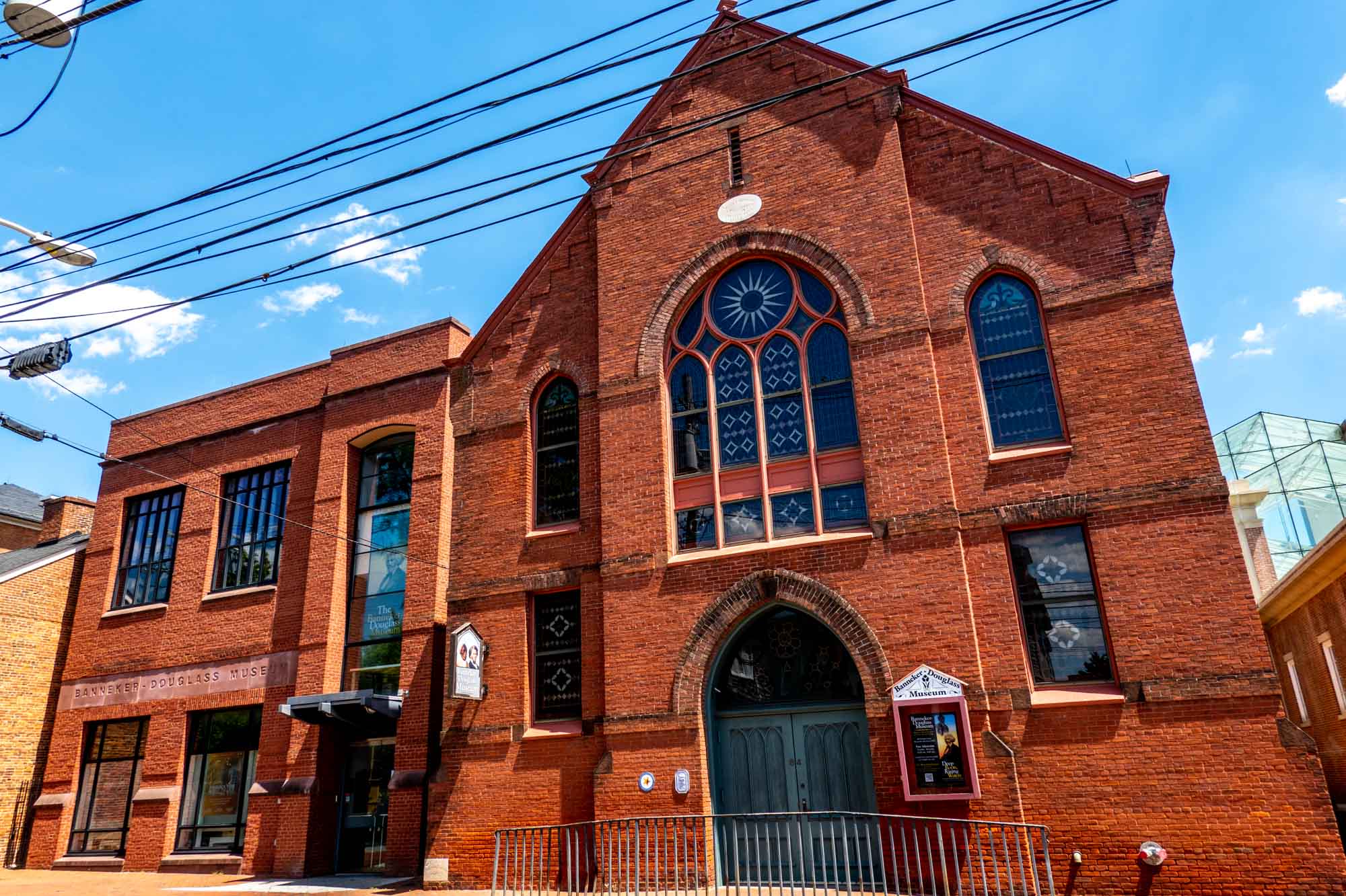 Exterior of a red brick church with stained glass windows.