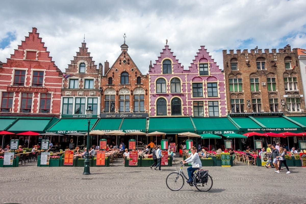 Person bicycling row of traditional buildings in Bruges