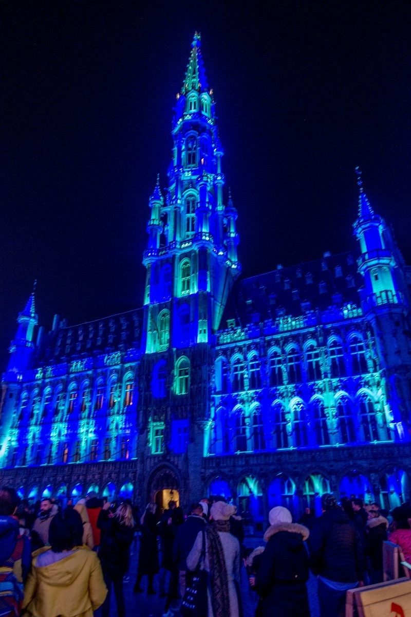 Building with a large tower lit up blue at night.