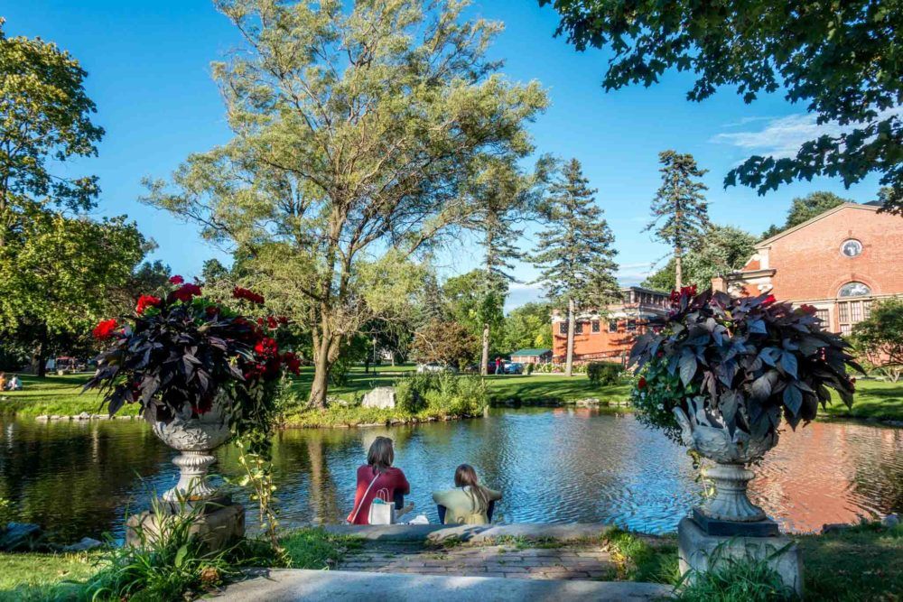 Women sitting by a pond surrounded by plants and trees