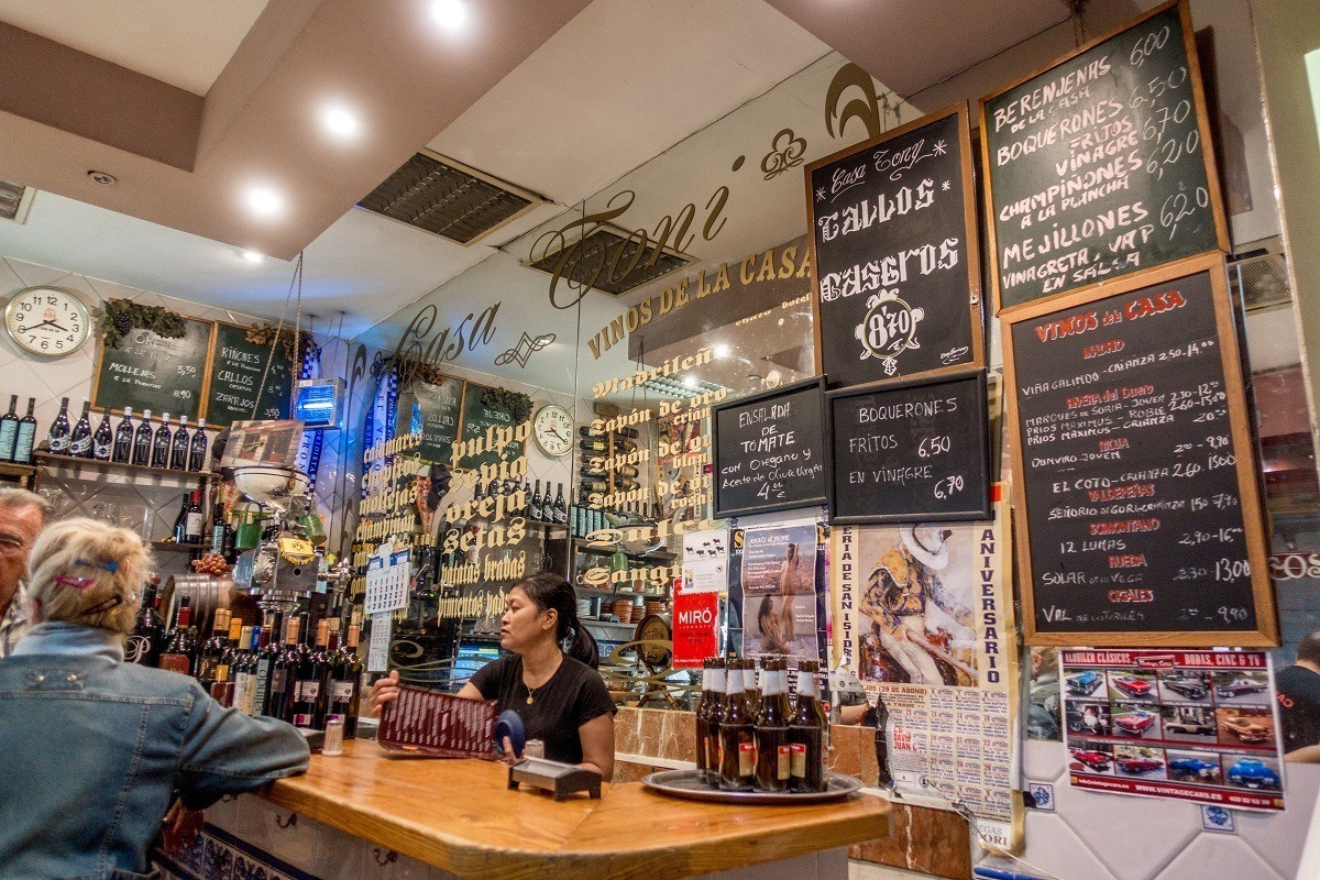 Wall covered with handwritten menus hanging behind a bar