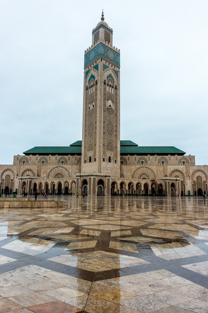 Exterior of a green and brown mosque with tall minaret 