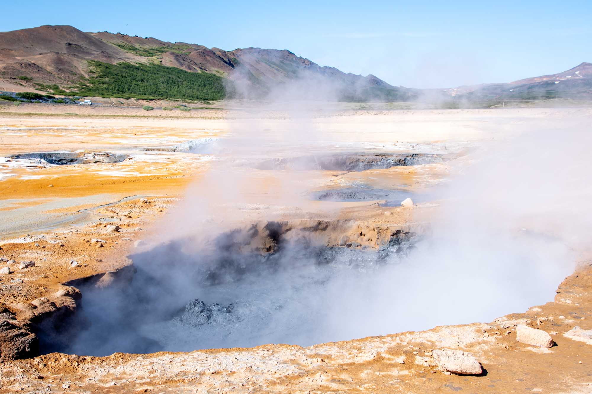 Boiling gray mud pits set among orange and white ground