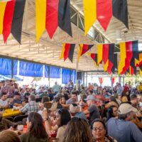 People sitting at tables under German flags at Oktoberfest in Fredericksburg