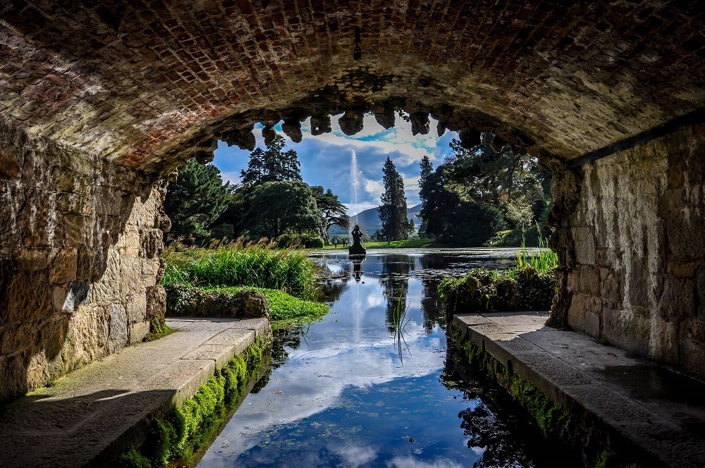 Fountain in a pond as seen through a tunnel