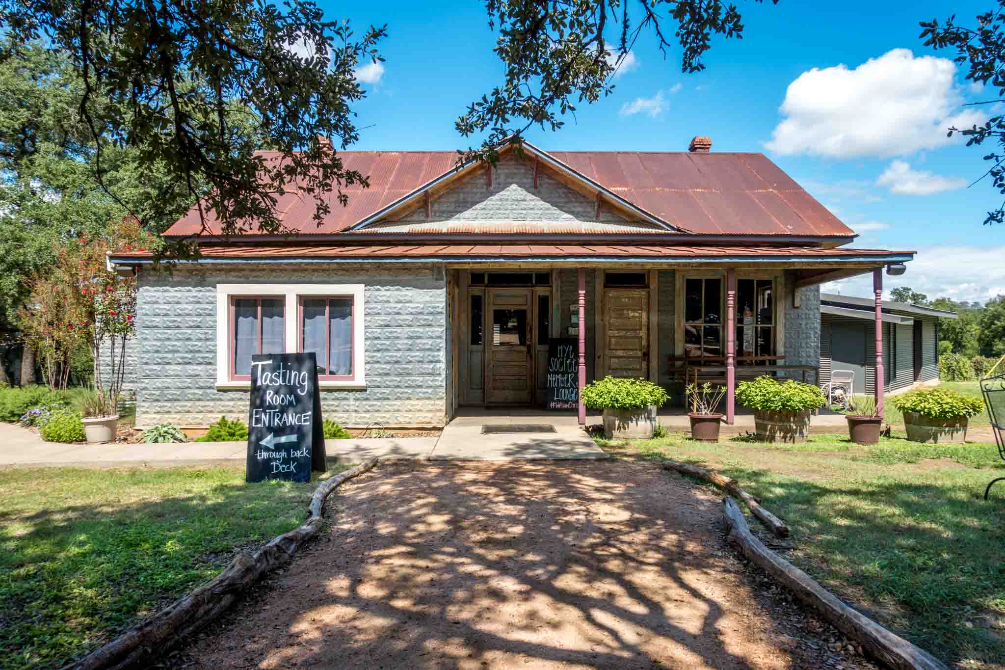 Exterior of an old building with sign: "Tasting room entrance through back deck"