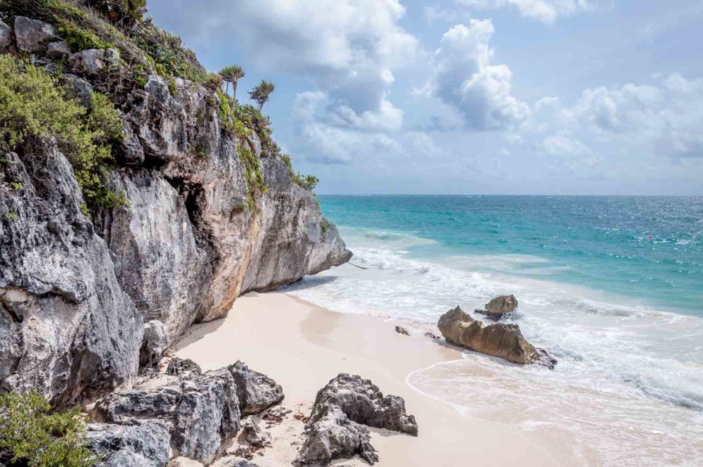 Rocky cliff ending at a sandy beach by the ocean