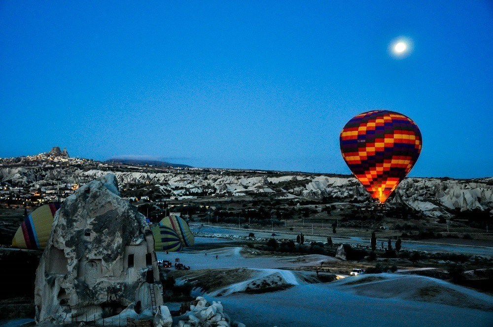 One of the Cappadocia Hot Air Balloons illuminated in the night sky under the moon