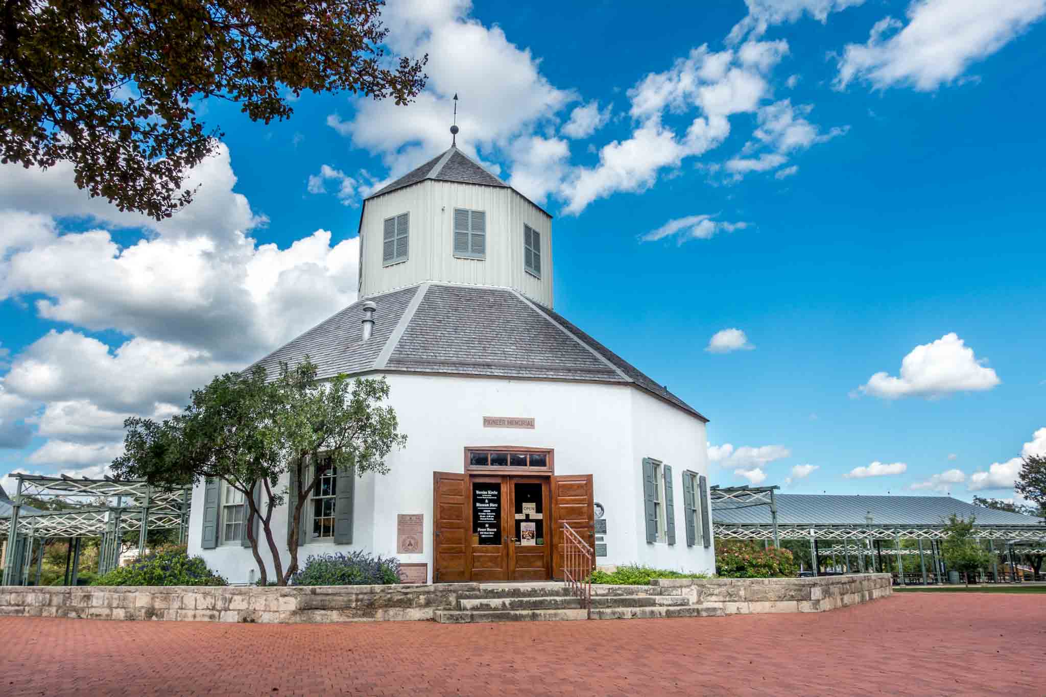 White octagonal building in a city square.