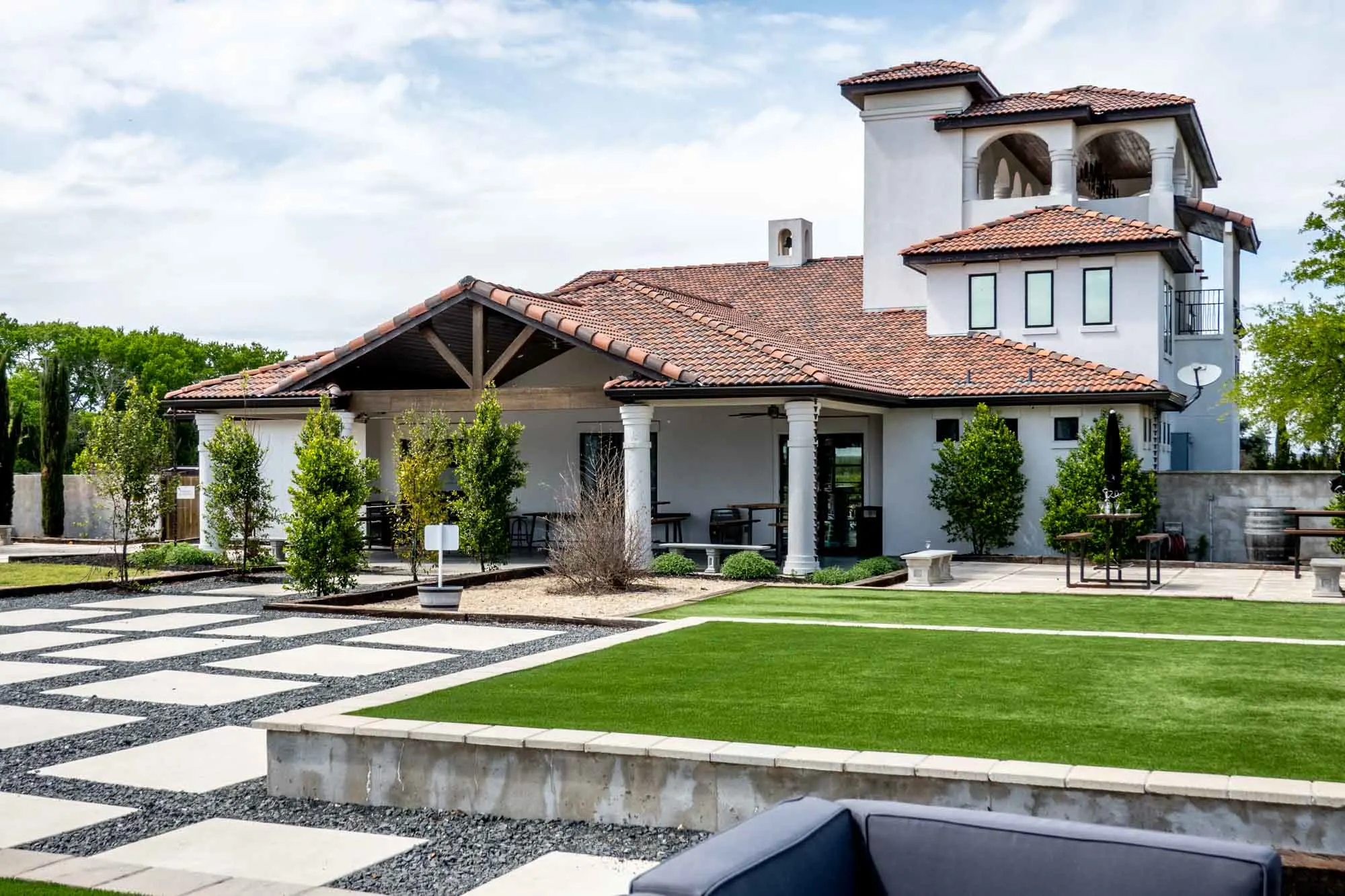 Patio area outside a large white building with a terra cotta tile roof