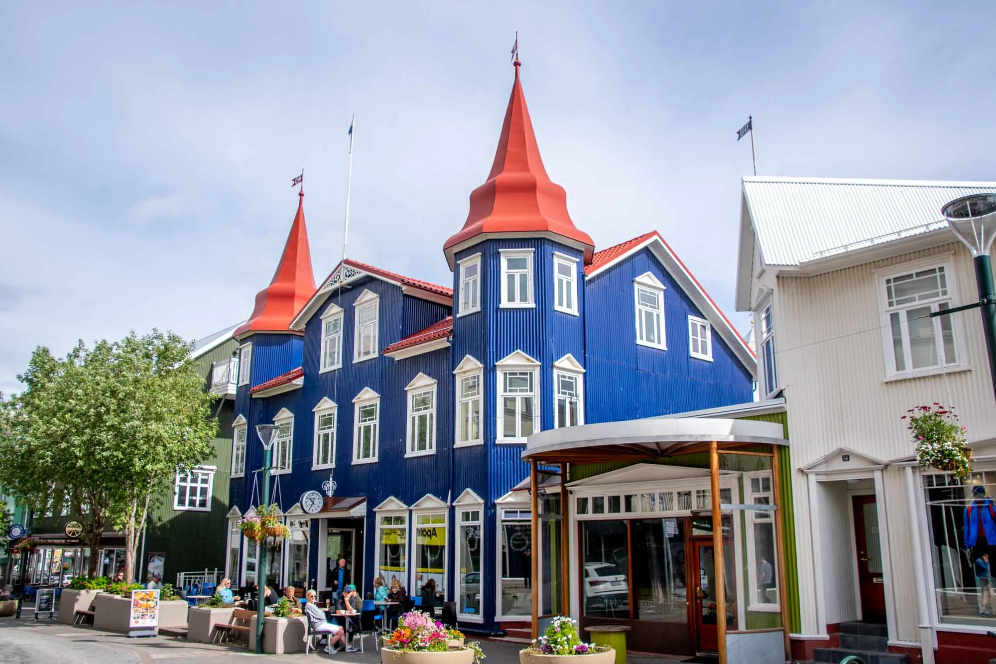 People at table outside a blue building with a red roof