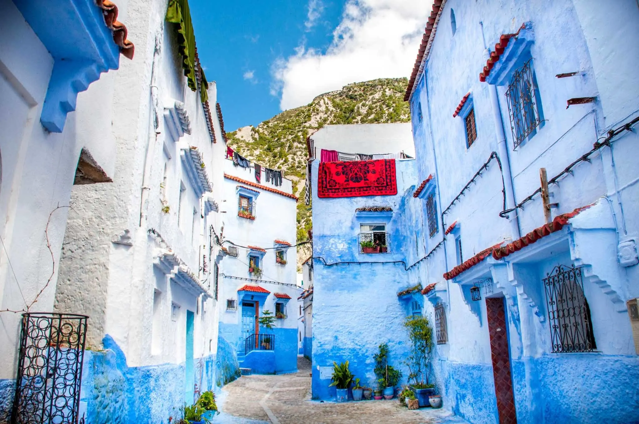 Blue and white street with a red carpet draped over a wall.