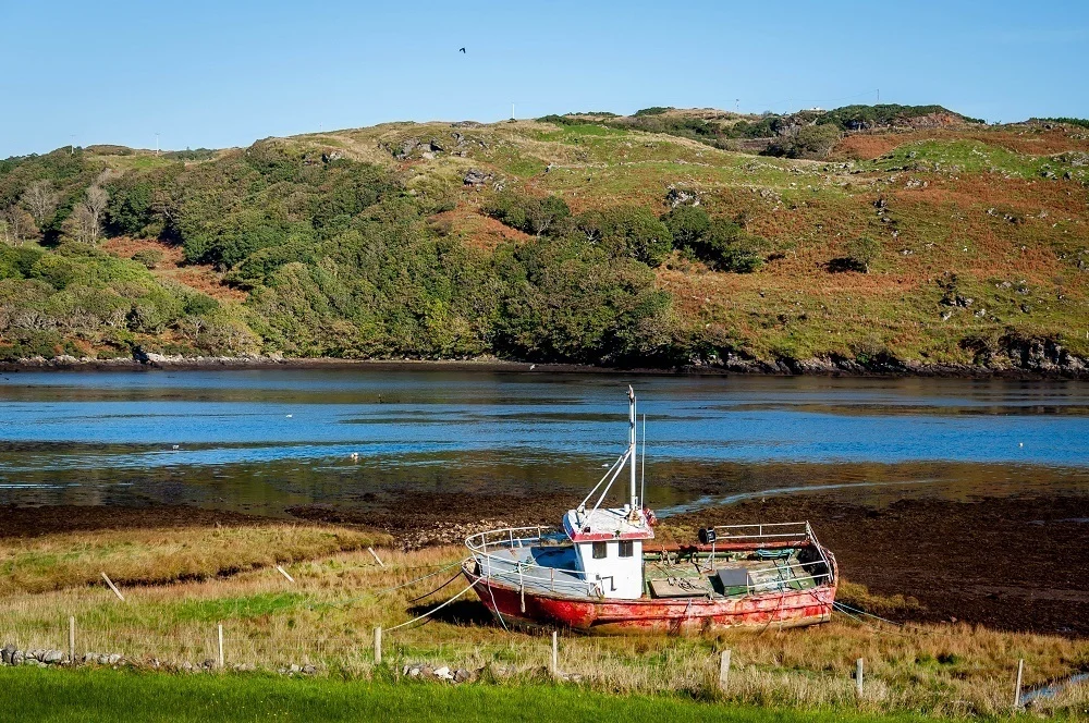 Boat on land with water and hill in the background