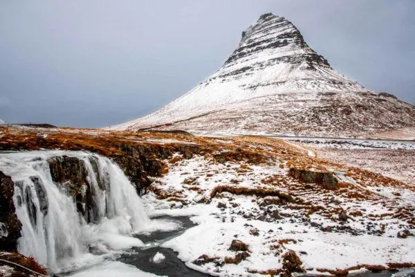 Snow-covered mountain beside a waterfall