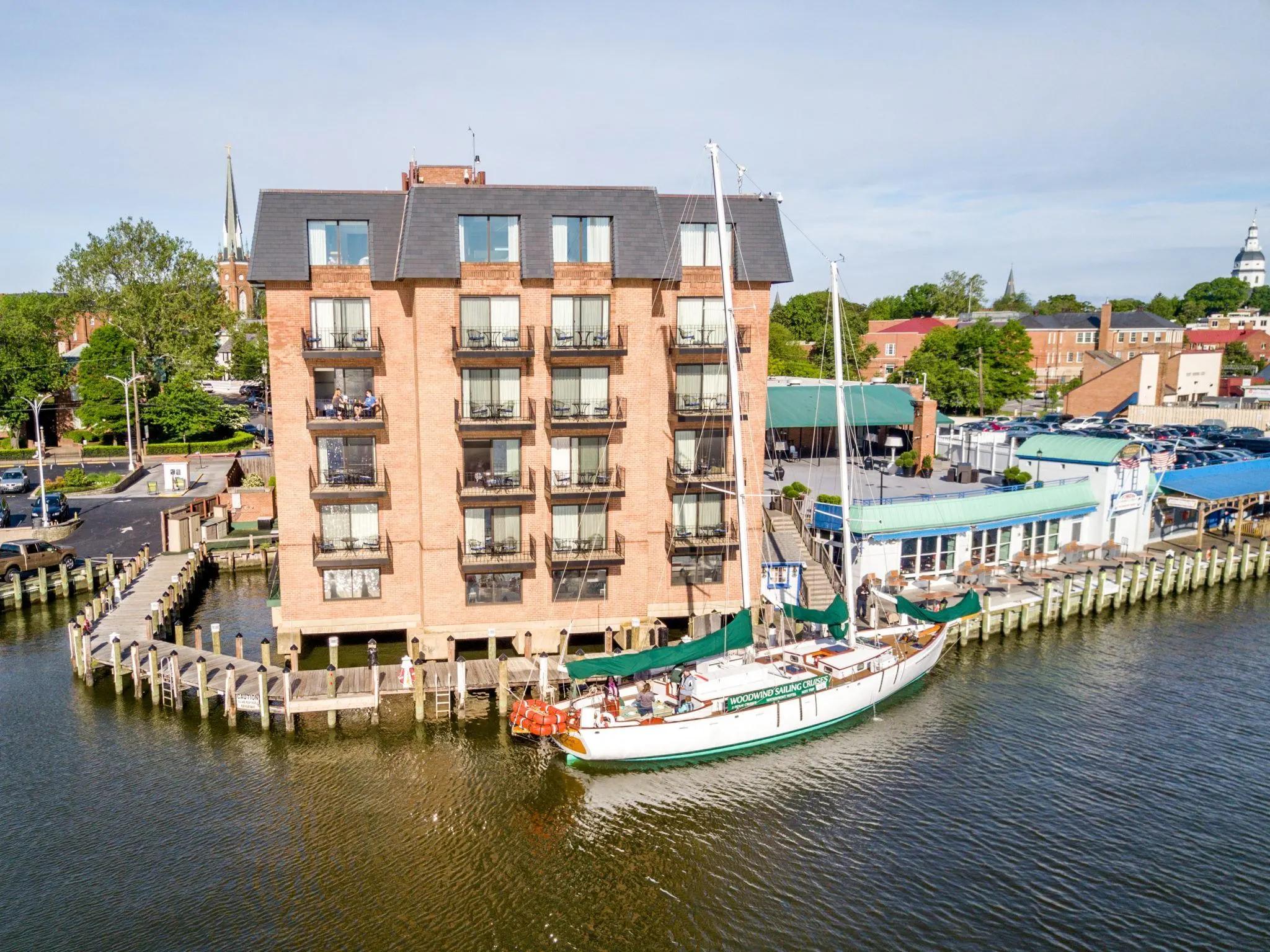 6-story building overlooking the water where a sailboat sits.