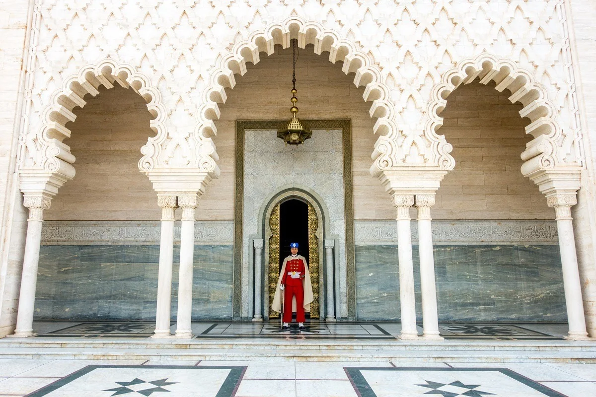 Man in a red uniform standing underneath white arches