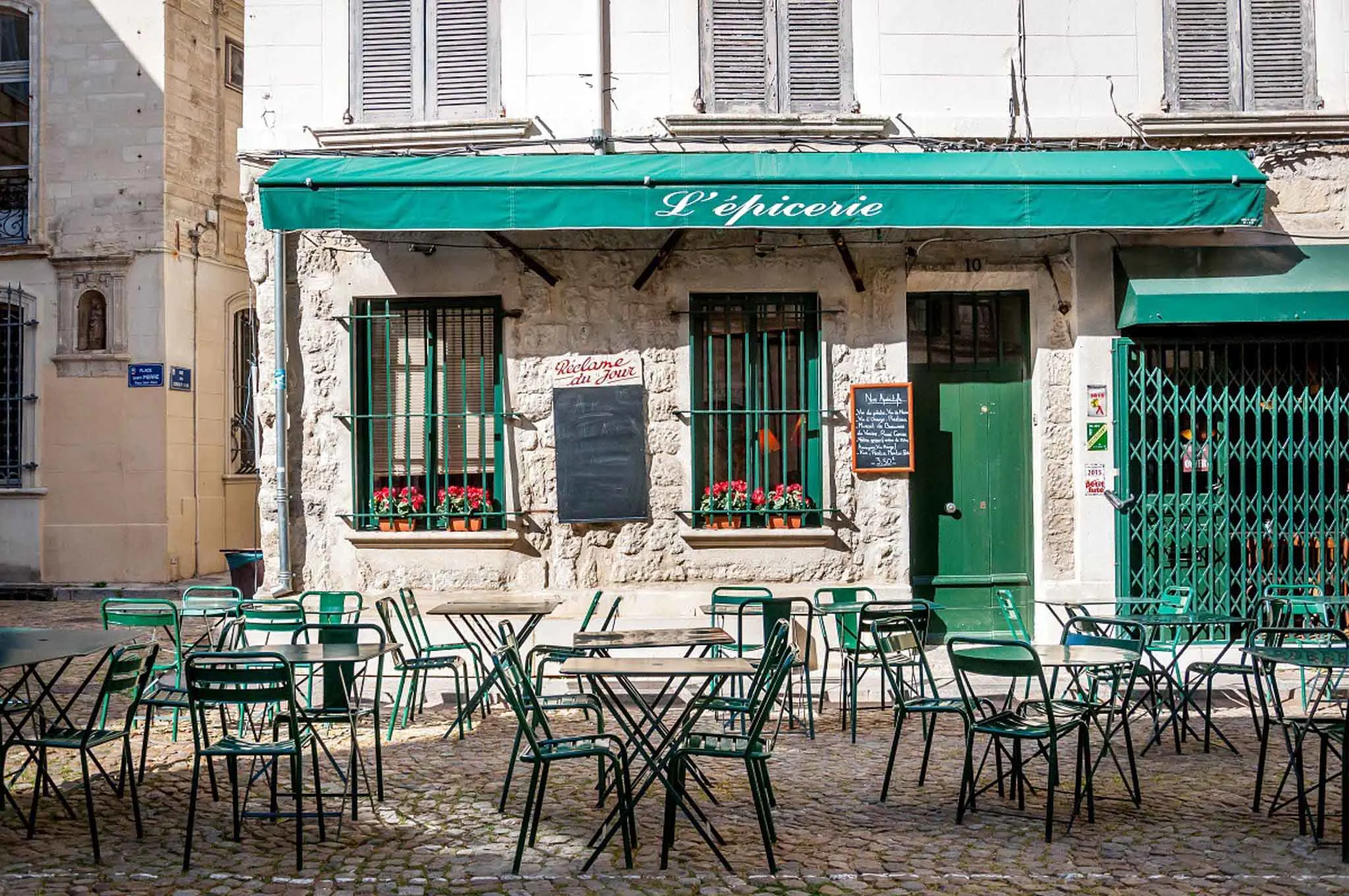 Green awning, tables, and chairs at a cafe