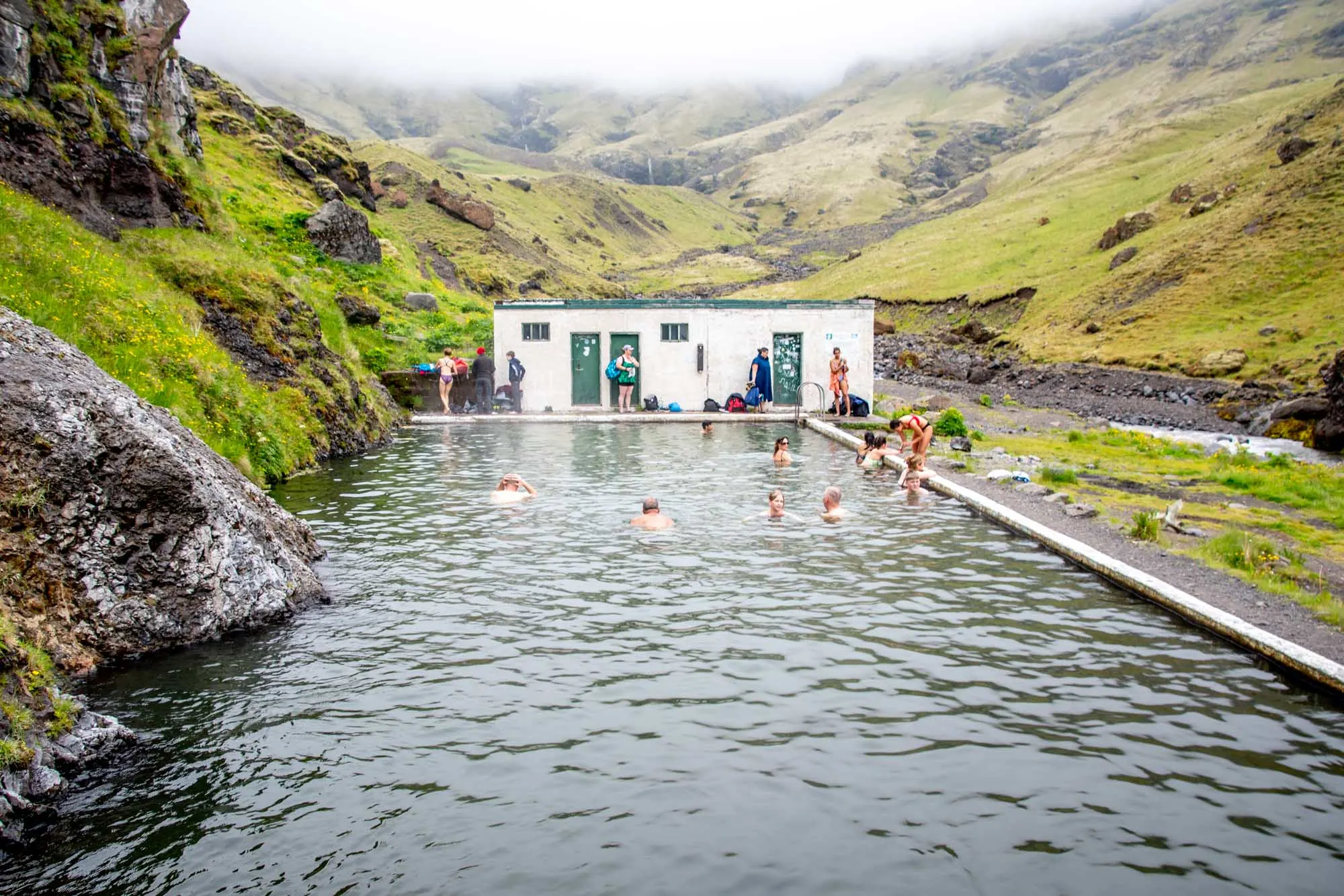 People swimming in a pool surrounded by mountains