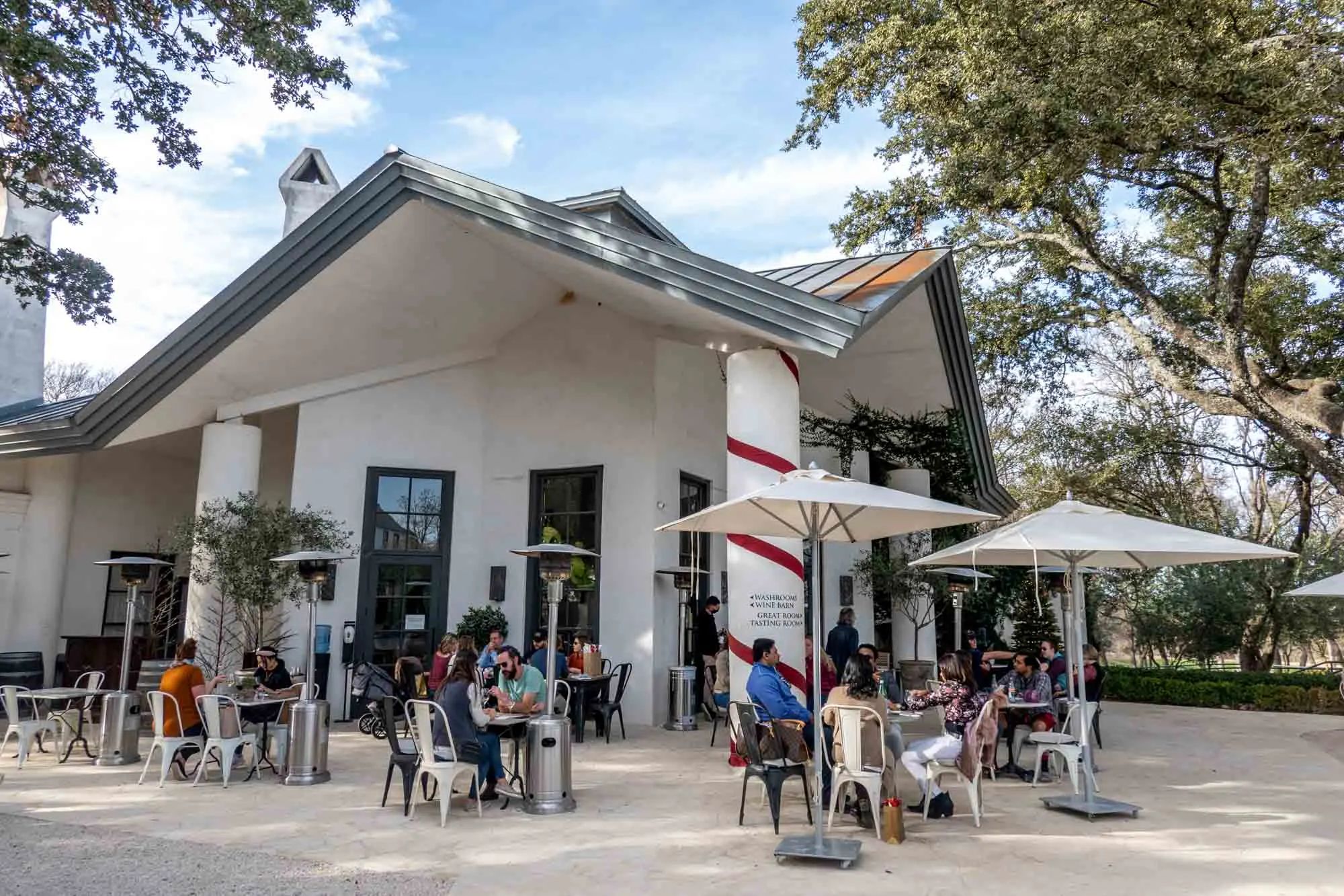 People sitting at tables outside a white building