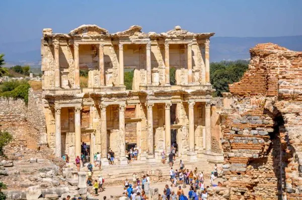 People at the base of an ancient wall with columns