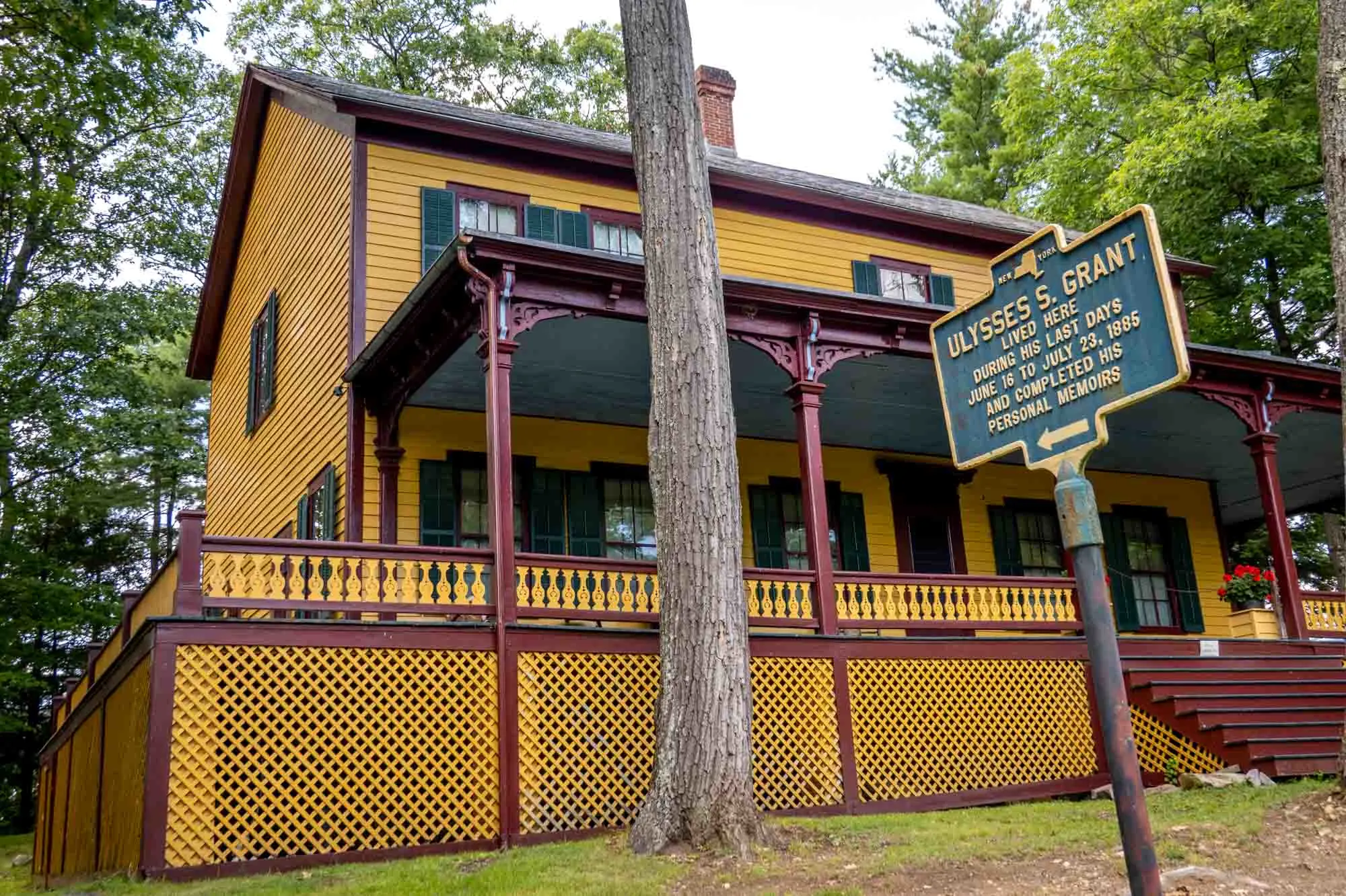 Yellow, green, and red painted building beside sign: Ulysses S. Grant lived here during his last days, June 16 to July 23, 1885, and completed his personal memoirs